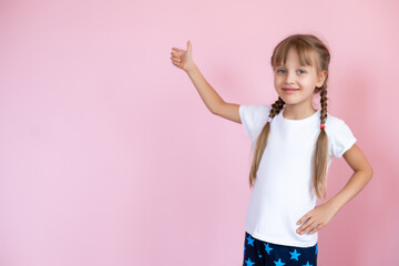 Beautiful little blonde girl with long hair in white T-shirt smiling on a pink background