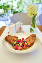 Tuna tartare with raspberries and blueberries in a white plate.