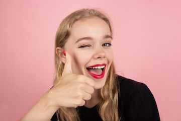 Thumbs up. Portrait of young emotional woman gesturing isolated on pink studio background. Human emotions, facial expression, sales, ad concept. Blonde caucasian pretty model gesturing. Copyspace.