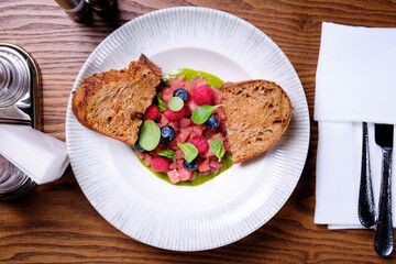 Tuna tartare with raspberries and blueberries in a white plate.