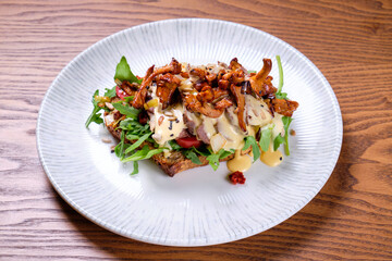 Bruschetta with roast beef and chanterelles on a plate.