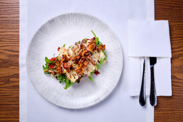 Bruschetta with roast beef and chanterelles on a white plate on a wooden table.