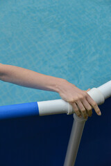 female hand on the edge of the pool