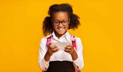 African Elementary School Girl Using Phone Playing Games In Studio