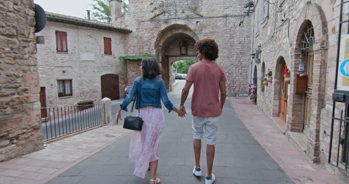 Romantic couple walking visiting rural town of Assisi.Back follow.Friends italian trip in Umbria.4k slow motion