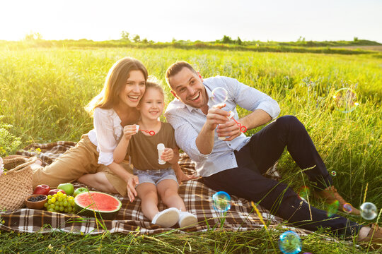 Happy lovely family playing together on a picnic in meadow