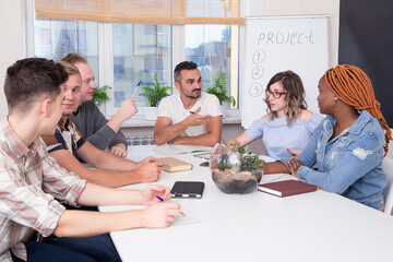 A group of multiracial people at a business training listens to the speaker or chief. Teamwork in an international IT company, students on seminar