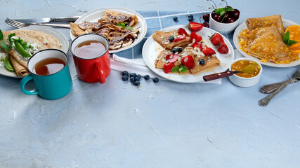 Variety of homemade crepes on grey background.