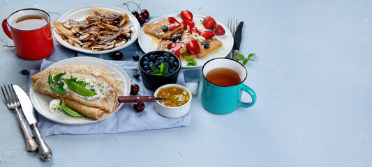 Variety of homemade crepes on grey background.