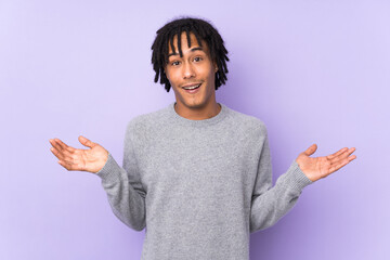 Young african american man isolated on purple background with shocked facial expression