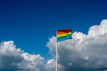 rainbow flag on front of a cloudy sky