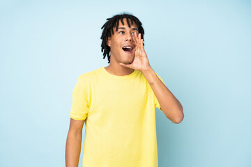 Young african american man isolated on blue background shouting with mouth wide open to the lateral