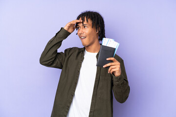 Young african american man isolated on purple background in vacation with passport and plane...