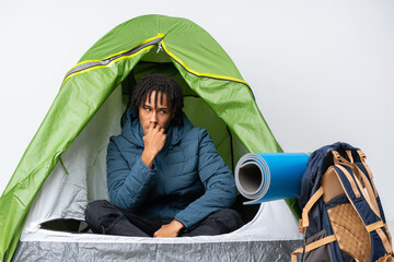 Young african american man inside a camping green tent nervous and scared