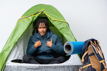 Young african american man inside a camping green tent pointing to oneself