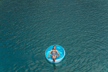 Fototapeta premium Young woman relaxing at the beach while sunbathing on a floating mattress