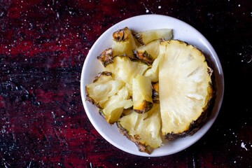 Pineapple Chunks in a Plate Isolated on Reddish Background With Copy Space