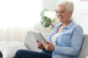 Apps For Seniors. Elderly lady using digital tablet while resting at home