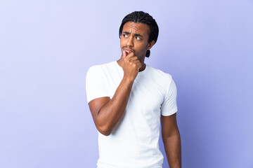 Young African American man with braids man isolated on purple background having doubts