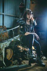Obraz na płótnie Canvas Post apocalyptic woman warrior in armor is sitting on the rusty engine.