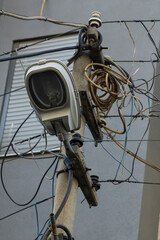Street light pole with many tangled cables near building,vertical image.