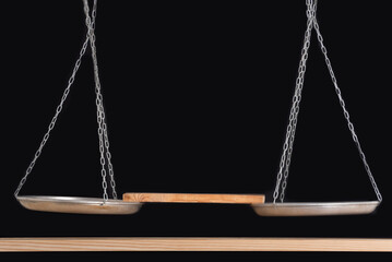 Balance scales and wooden shelf on black background. Front view. Copy space.