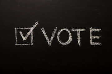 Obraz premium Vote tick on chalkboard, black background, elections 2020
