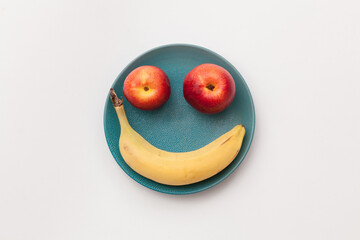 face made of fruits in a blue plate on a white background