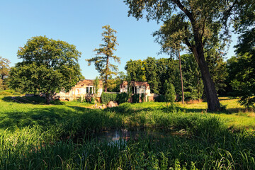 Classic wide-angle landscape view of ancient ruins with small waterfall and pond in Alexandria park in Bila Tserkva, Ukraine. Famous touristic place and romantic travel destination. Summer sunny day - obrazy, fototapety, plakaty