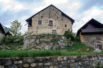 Fototapeta na wymiar View of a typical house of the Hautes-Alpes. The stone of the country has grey tints and is covered with lime in places. The house is built on a boulder.