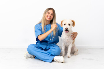 Young veterinarian woman with dog sitting on the floor proud and self-satisfied