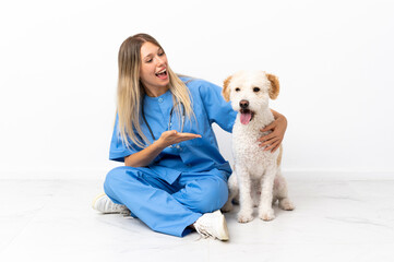 Young veterinarian woman with dog sitting on the floor with surprise expression while looking side