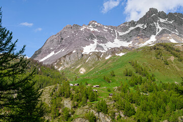 The snowy summits dominate the green mountain pastures. A few chalets have been converted into second homes. A forest of larches grows on the slopes of the mountain pastures.