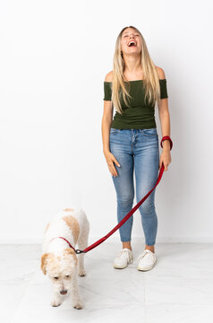Young Caucasian Woman Walking The Dog Isolated On White Background Laughing