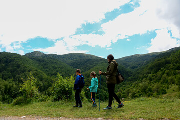 Mother and two children enjoying a walk in the mountain trail, side view.