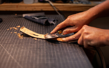 Hands of female leather artisan creating a hand-made belt