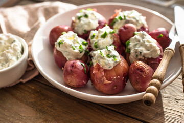 Young, boiled potatoes withLabneh middle eastern lebanese cream cheese and green onion on a wooden...