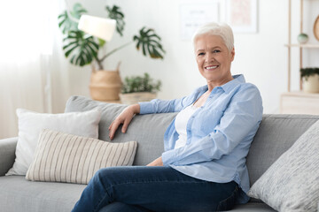 Portrait of senior woman relaxing on sofa at home, enjoying retirement time