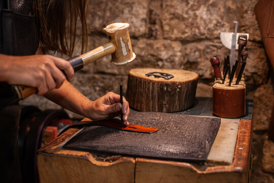 Hands of female leather artisan creating a hand-made belt - Powered by Adobe