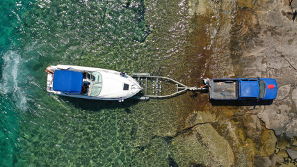 Aerial top view photo of inflatable speed boat on trailer being towed by truck from emerald exotic sea to land