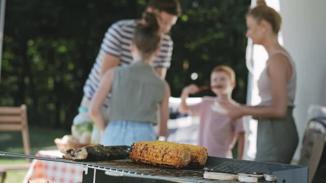 Video of grilled corn against the background of bustling family. Shot with RED helium camera in 8K.