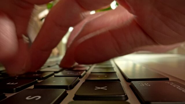 Fingers pressing buttons of laptop typing text, sending massage, doing creative job, searching for information online. Shot with probe lens, 4K