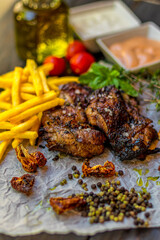 Delicious piece of meat served with potatoes decorated with dry tomatoes, pepper and herbs