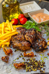 Delicious piece of meat served with potatoes decorated with dry tomatoes, pepper and herbs
