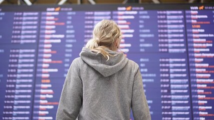 Woman tourist on the background of information board at the airport.