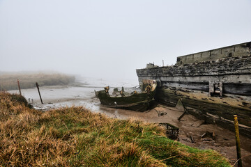 Oare, Faversham, Kent, UK. Derelict boats at Oare Creek. Low tide and early morning mist.