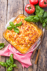 Traditional italian lasagna with vegetables, basil, minced beef meat, tomato and cheese on wooden  background.
