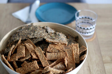 Two types of seed crackers, served in a big bowl on a table. Selective focus.