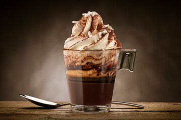 Cup of coffee with whipped cream, milk foam, sugar and cocoa powder.