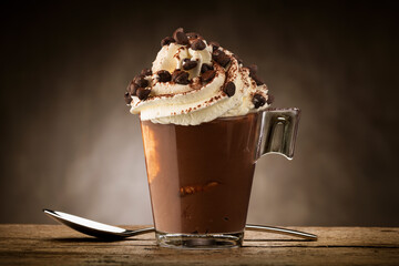 Cup of coffee with whipped cream, cocoa powder and chocolate chips.